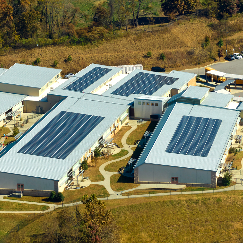 Aerial view of a large commercial or public building with flat roof solar panel installation - ideal for schools and businesses in Bicester exploring solar energy